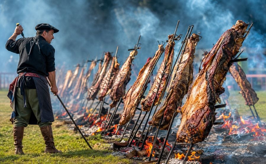 Hombre haciendo asado a la estaca en el campo.